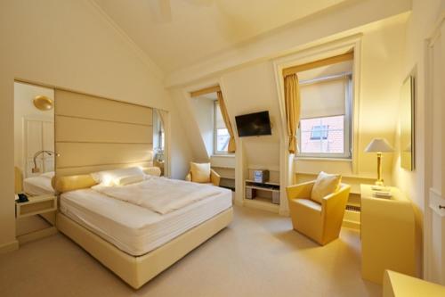 a bedroom with a large white bed and a chair at President Mezonet Apartment in Brno