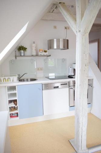 a white kitchen with white appliances and a staircase at Ferienwohnung Hafenwestseite Neustadt in Neustadt in Holstein