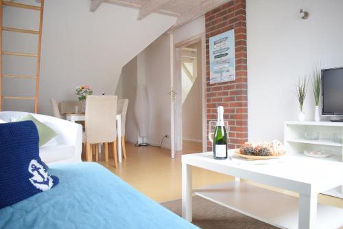 新城荷斯坦的住宿－Ferienwohnung Hafenwestseite Neustadt，客厅配有沙发和一张桌子及一瓶葡萄酒