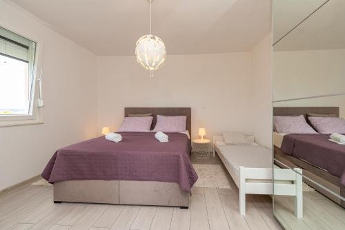 a white bedroom with two beds and a mirror at Vila Luna Apartments in Zadar