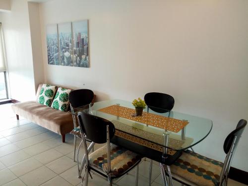 a dining room with a glass table and chairs at Forbes Area BGC Taguig Manila in Manila