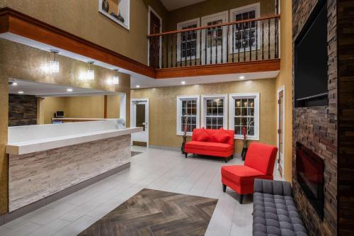 a lobby with two red chairs and a fireplace at Ramada by Wyndham Groton in Groton