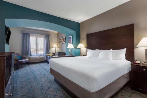 a hotel room with a large bed and a desk at La Quinta by Wyndham Columbus West - Hilliard in Columbus