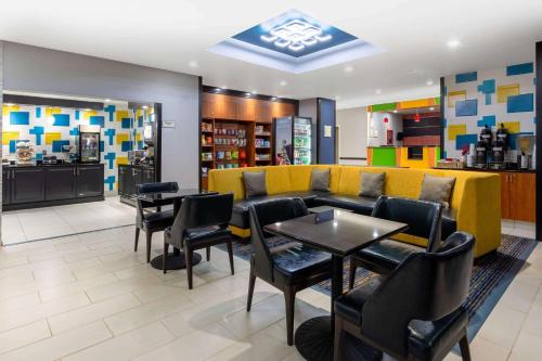 a restaurant with a yellow couch and tables and chairs at La Quinta by Wyndham Columbus West - Hilliard in Columbus