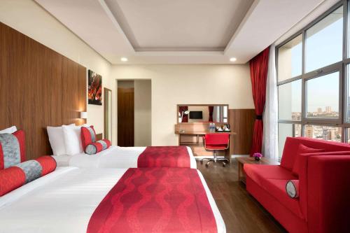 a hotel room with a large bed and a red couch at Ramada Encore by Wyndham Kuwait Downtown in Kuwait