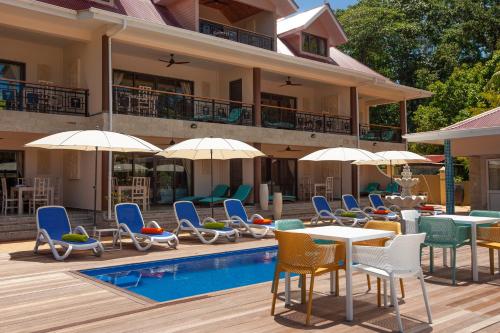 a resort with chairs and tables and a swimming pool at Casa De Leela Self Catering Guest House in La Digue