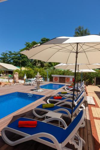 a row of lounge chairs and an umbrella next to a pool at Casa De Leela Self Catering Guest House in La Digue