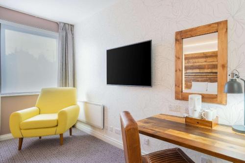 a living room with a tv and a chair at Clarion Cedar Court Bradford Hotel in Bradford