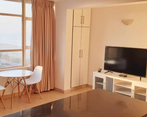 a living room with a flat screen tv and a table at 904 Tenbury Beach Apartment in Durban