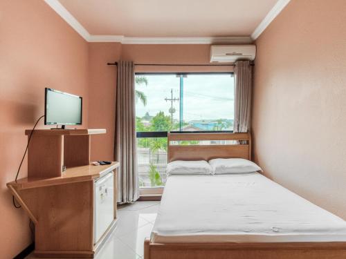1 dormitorio con 1 cama, TV y ventana en Hotel Cardozo, en Parobé