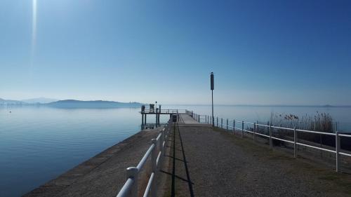 a pier on a lake with a blue sky at Appartamento "IL GAMBERO" in Magione