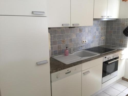 uma cozinha com armários brancos e um lavatório em Strandjutter huisje 8 em Middelkerke