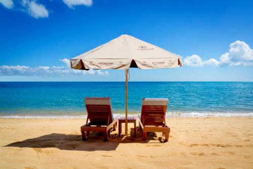 twee stoelen en een parasol op het strand bij Astagina Resort Villa and Spa in Legian