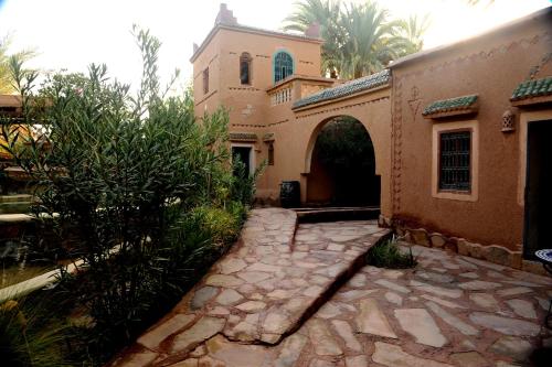 a house with a stone walkway next to a building at Le Chant Des Palmiers in Agdz