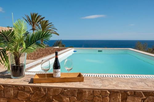 a bottle of wine and two glasses next to a swimming pool at Villa del Mar Esquinzo Jandia Fuerteventura in Playa Jandia