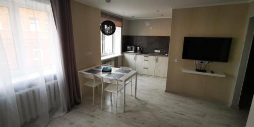 a kitchen with a table and chairs and a television at Central Moon in Daugavpils