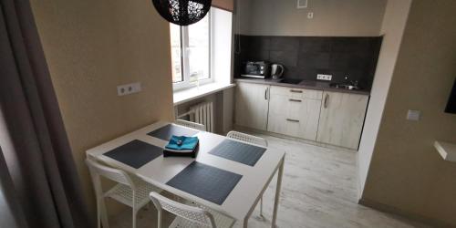 uma pequena cozinha com uma mesa branca e cadeiras em Central Moon em Daugavpils