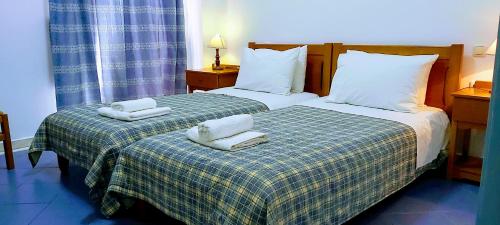 twee bedden in een hotelkamer met handdoeken erop bij Gerasimos in Menídion