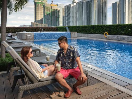 a man and woman sitting in chairs next to a pool at Shangri-La The Fort, Manila in Manila