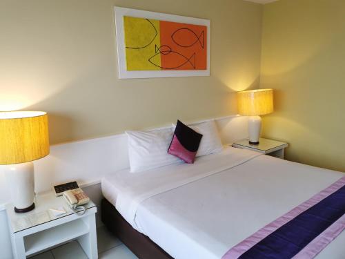 a bedroom with a white bed with two lamps and two tables at Tongtara Riverview Hotel in Bangkok