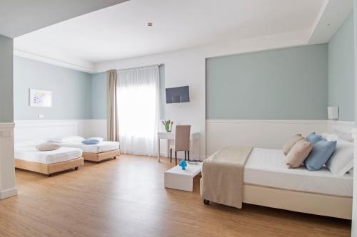 a white bedroom with two beds and a desk at Regiohotel Manfredi in Manfredonia