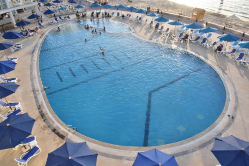 a large pool with blue umbrellas and people in it at Golden Jewel Hotel in Alexandria