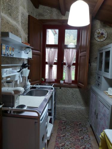 una cocina con fregadero y ventana en A Casa da Carballa, en Ponteareas
