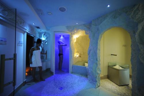 a man standing in a bathroom with a sink and a tub at Parc Hotel Flora S in Riva del Garda