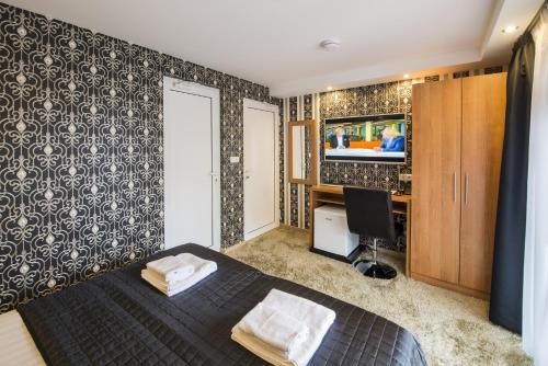 a bedroom with a bed and a desk and a television at Villa Monte Dana in Zwanenburg