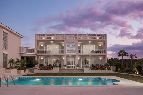 a large house with a swimming pool in front of it at Luxury Rooms Vila Carissa in Malinska