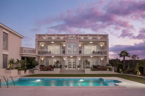 una grande casa con una piscina di fronte di Luxury Rooms Vila Carissa a Malinska
