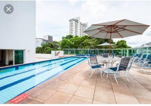 a swimming pool with a table and an umbrella at Flat Luxo Afonso Pena - Savassi/Serra/Mangabeiras in Belo Horizonte