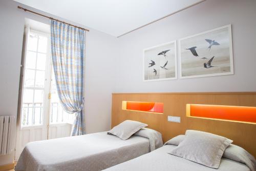 two beds in a room with birds on the wall at Casa Celsa-Barbantes in Santiago de Compostela