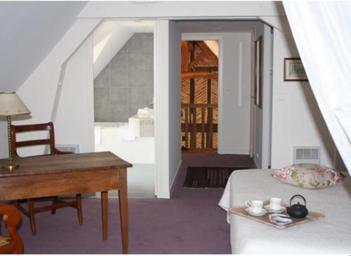 een kamer met een bureau, een bed en een tafel bij La rabouillere in Contres