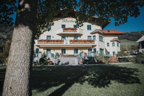 a large white building with a tree in the foreground at Appartements Wieshof in Sankt Johann im Pongau