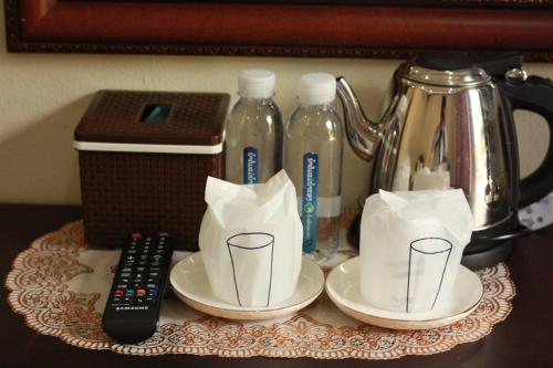 a table with two cups and a kettle and a remote control at 888guest house in Luang Prabang