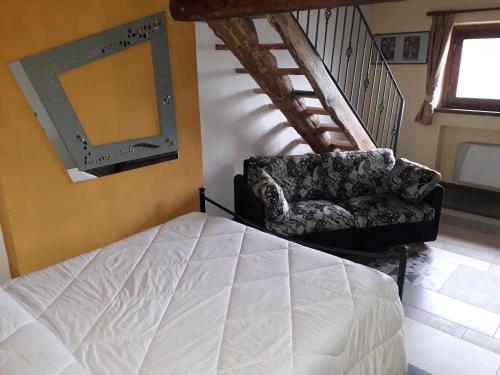 a bedroom with a bed and a chair and a staircase at Agriturismo Il Balcone sulla Valle in Bedero Valcuvia