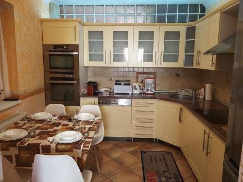 a kitchen with a table and chairs and a kitchen with white cabinets at Édenkert Apartmanház in Kisvárda