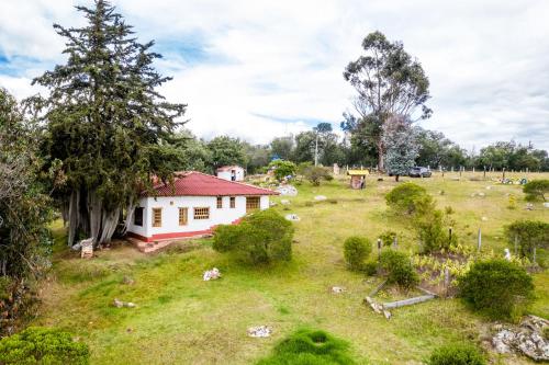 a small white house in a field with trees at Finca El Pedregal Guatavita in Guatavita