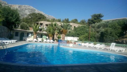 a large swimming pool with chairs and a house at Ilias Studios sevasti in Panormos Kalymnos