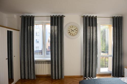 ein Schlafzimmer mit einer Uhr an der Wand und Vorhängen in der Unterkunft Apartament Basia in Hajnówka