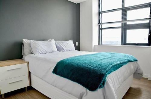 a bedroom with a bed with a green blanket on it at Matrix Luxury 2 bedroom Apartments Century City, Cape Town in Cape Town