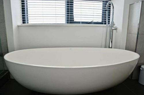 a white bath tub in a bathroom with a window at Matrix Luxury 2 bedroom Apartments Century City, Cape Town in Cape Town
