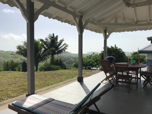 a porch with a hammock and a table and chairs at Villa Bwa Kannel in La Trinité