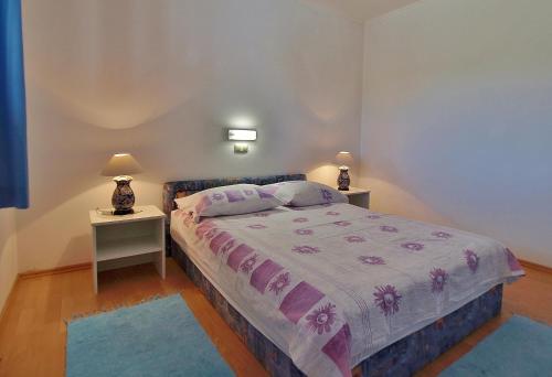 a bedroom with a bed with two night stands and two lamps at Apartments Eufemija in Rab