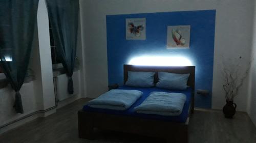 1 dormitorio con 1 cama con pared azul en Olsinky en Ústí nad Labem