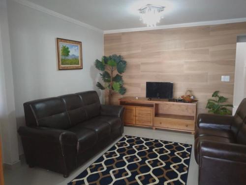 sala de estar con sofá de cuero y TV en Bela casa, en Arraial do Cabo
