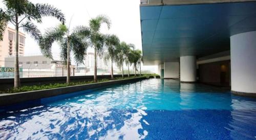a large swimming pool with palm trees in a building at Taragon Putrie Bintang suites in Kuala Lumpur