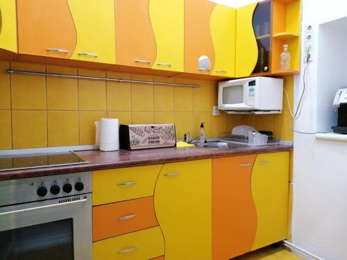 a kitchen with yellow and orange cabinets at Apartament JOSEFIN in Timişoara