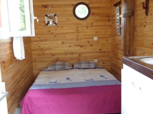 1 dormitorio en una cabaña de madera con 1 cama. en La Roulotte CHAINOUX, en Bains-sur-Oust